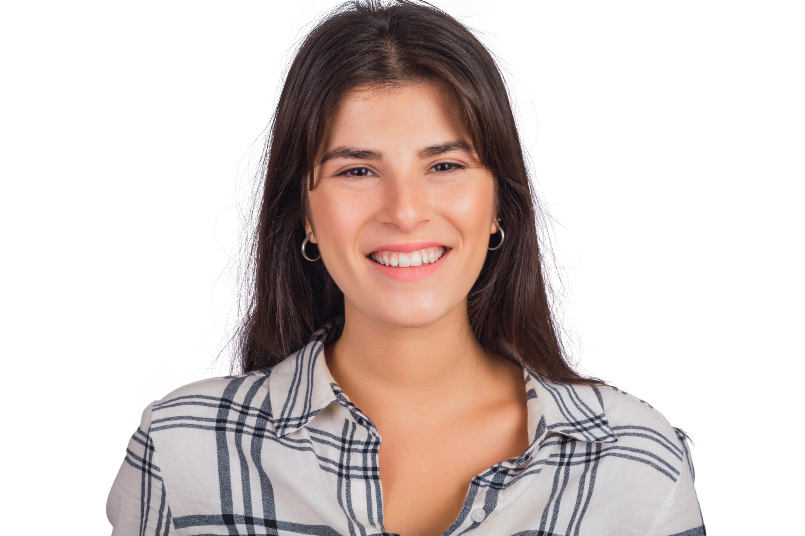 Portrait of young beautiful woman looking at camera and smiling in studio against white background.